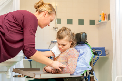disabled child in a wheelchair being cared for by a nurse