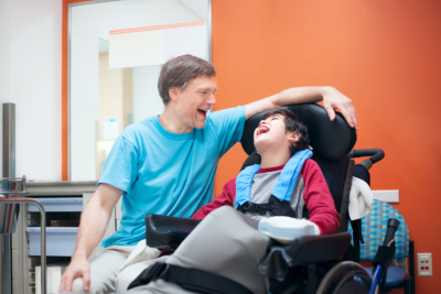 Father talking with disabled biracial son sitting in wheelchair 